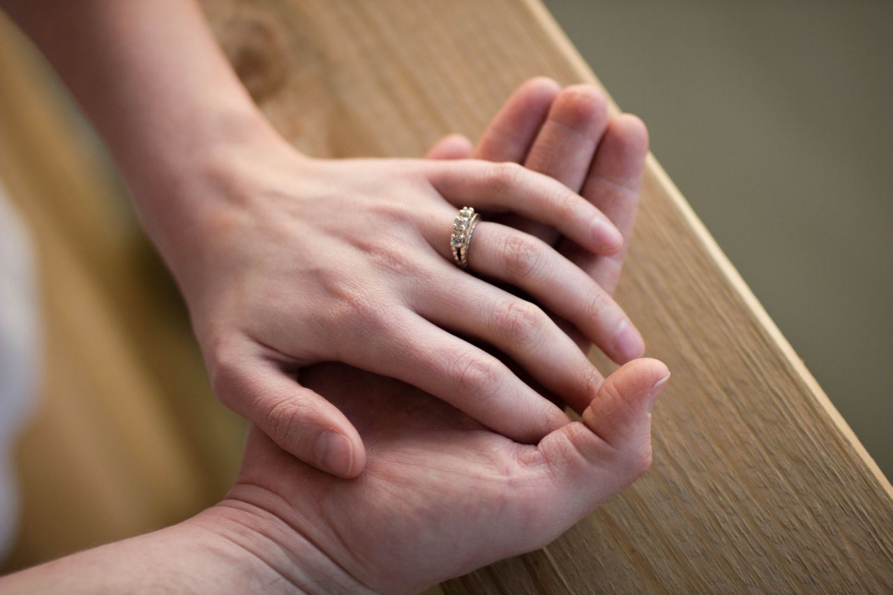 An engaged couple holding hands, the engagement ring in clear view.