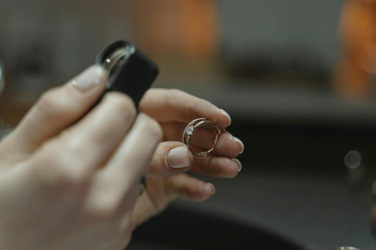 a jeweler holding a diamond ring and inspecting it with a magnifying glass