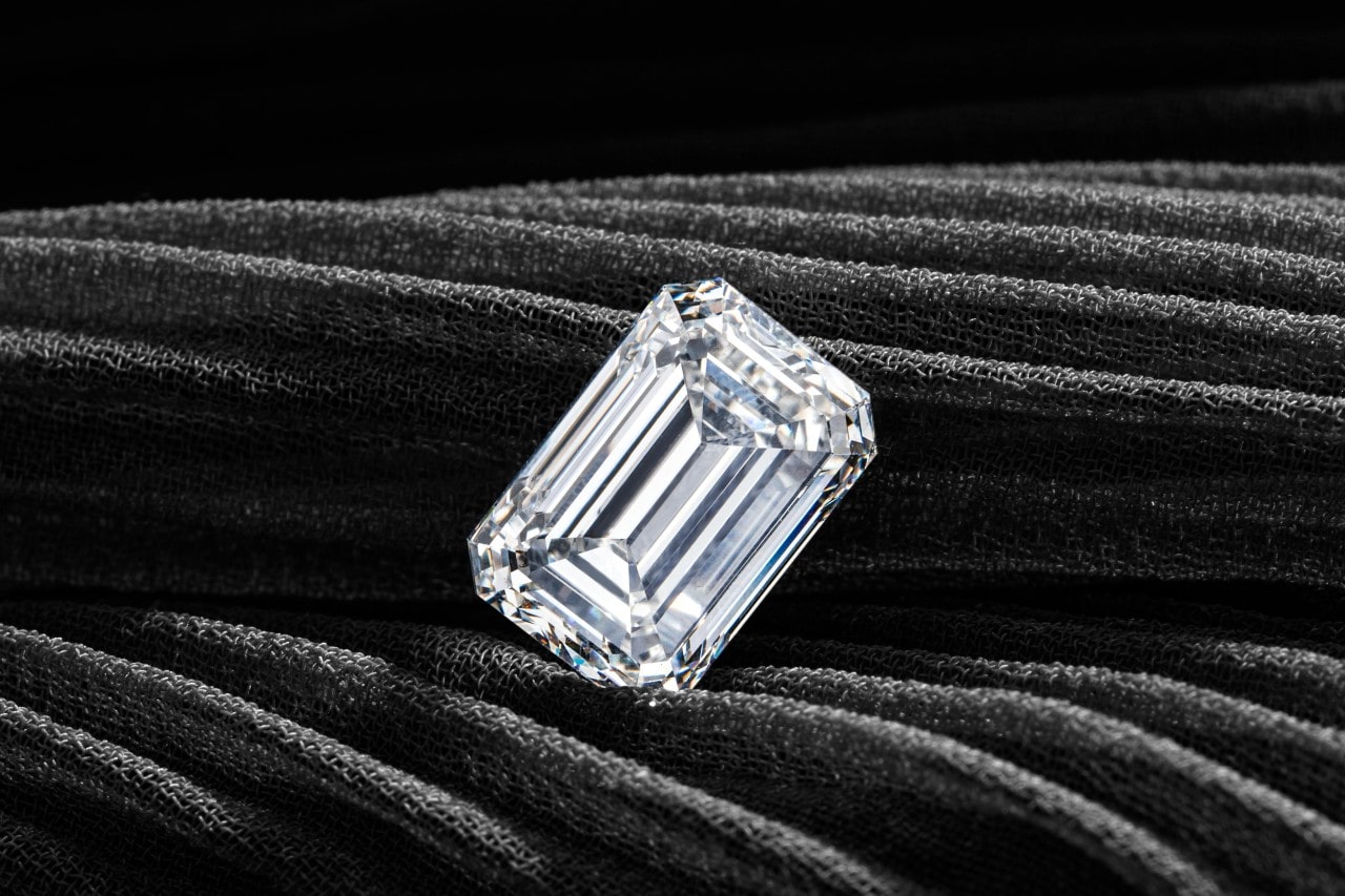 an emerald cut diamond on a piece of dark gray fabric