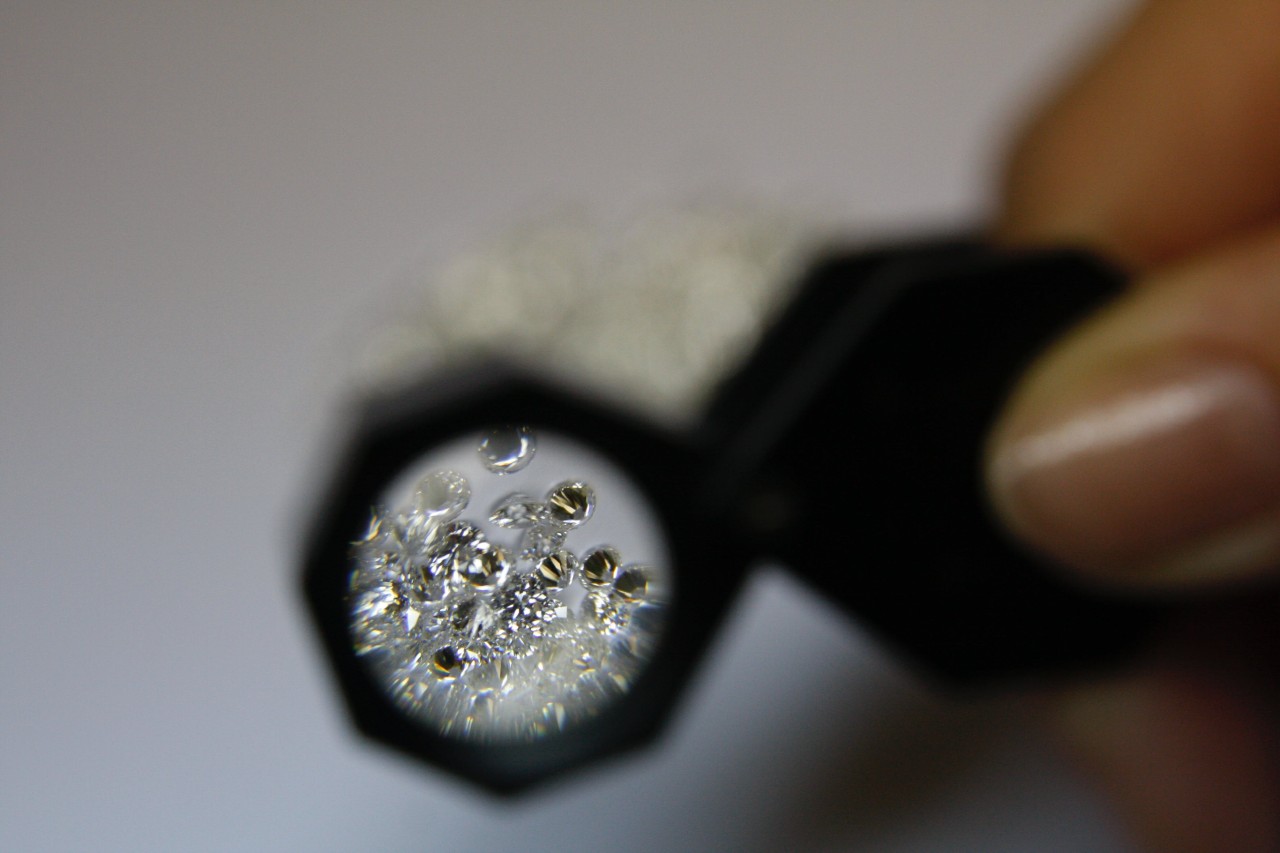 a person looking at diamonds through a magnifying glass