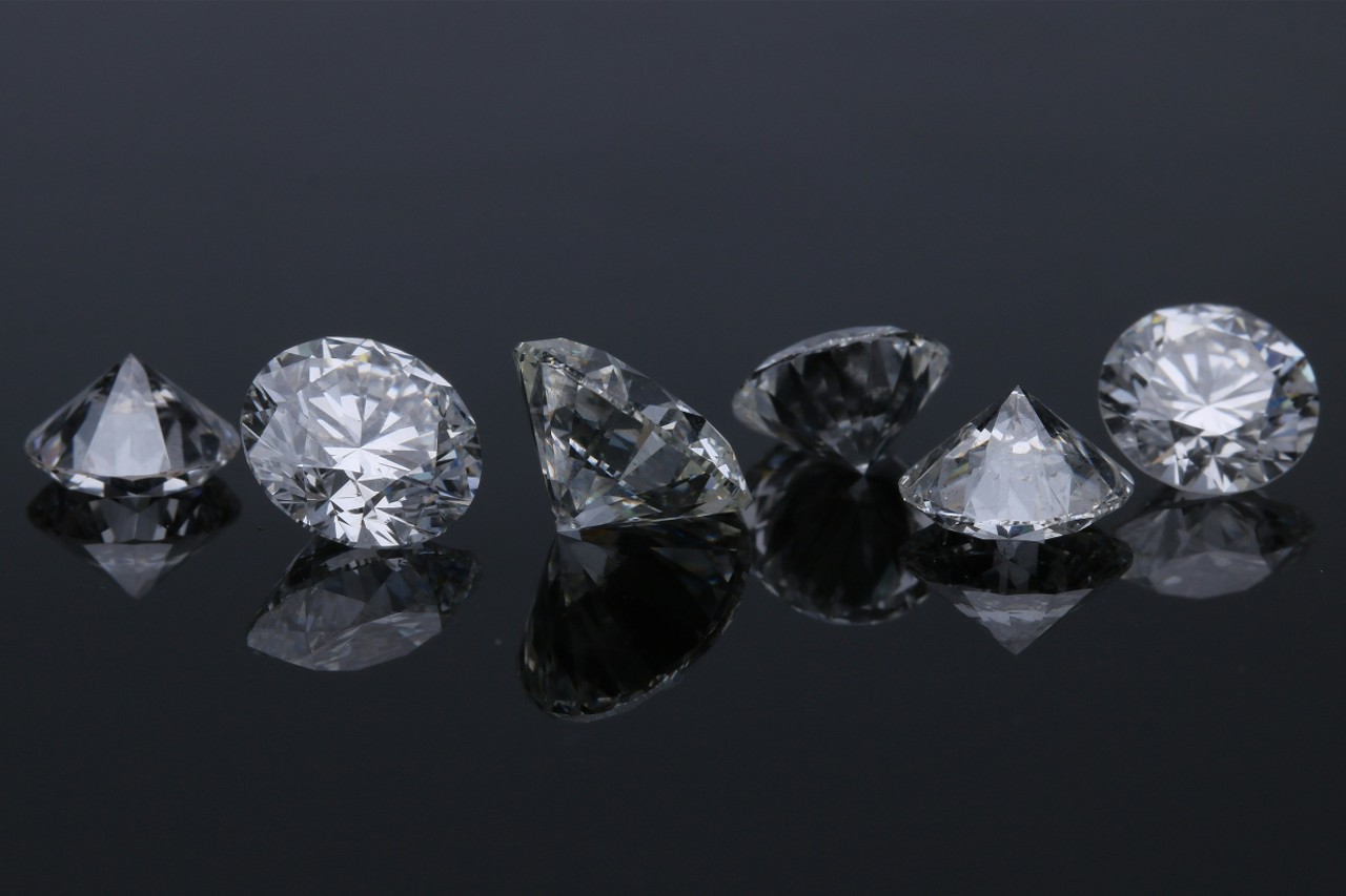 six round cut diamonds in a line on a black, reflective surface