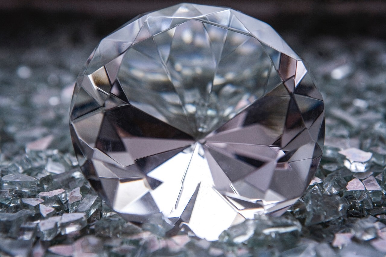 a very close up image of a round cut diamond lying among glass shards