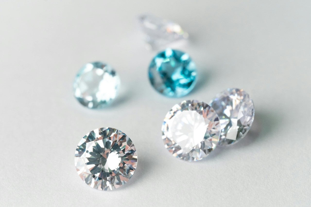 six diamonds, some clear, some blue, on a white surface