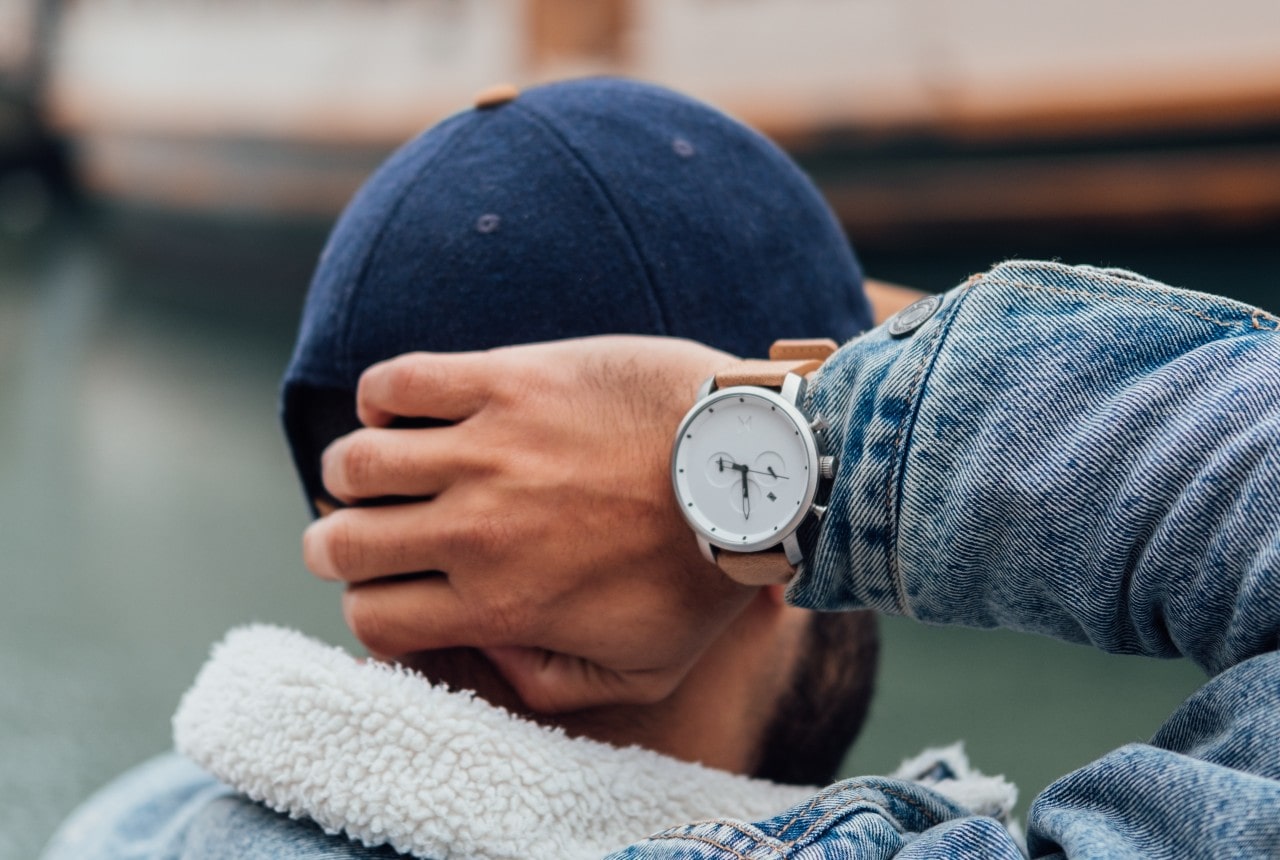 A comfortably dressed man wearing a minimalist wrist watch.