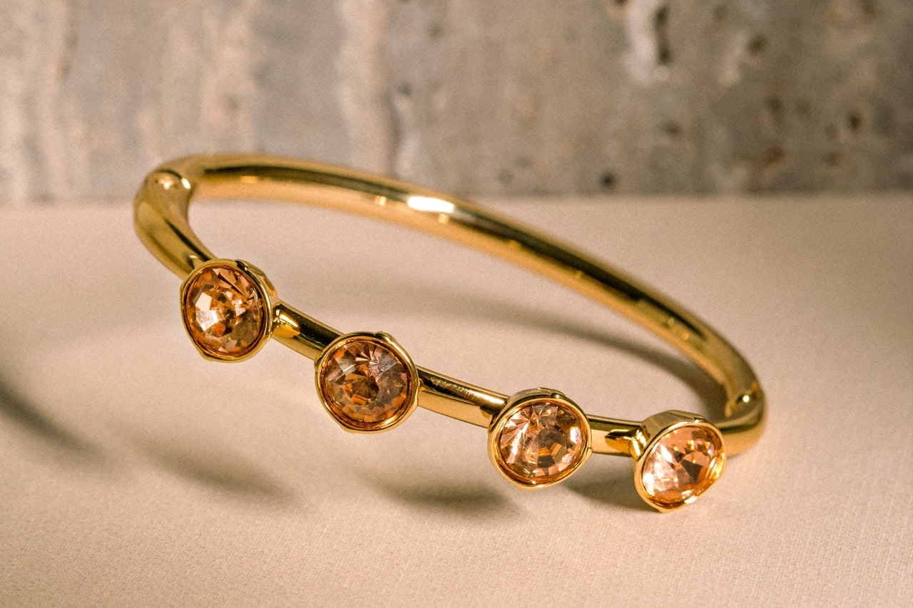 a yellow gold fashion ring set with four circle cut citrine on a beige surface