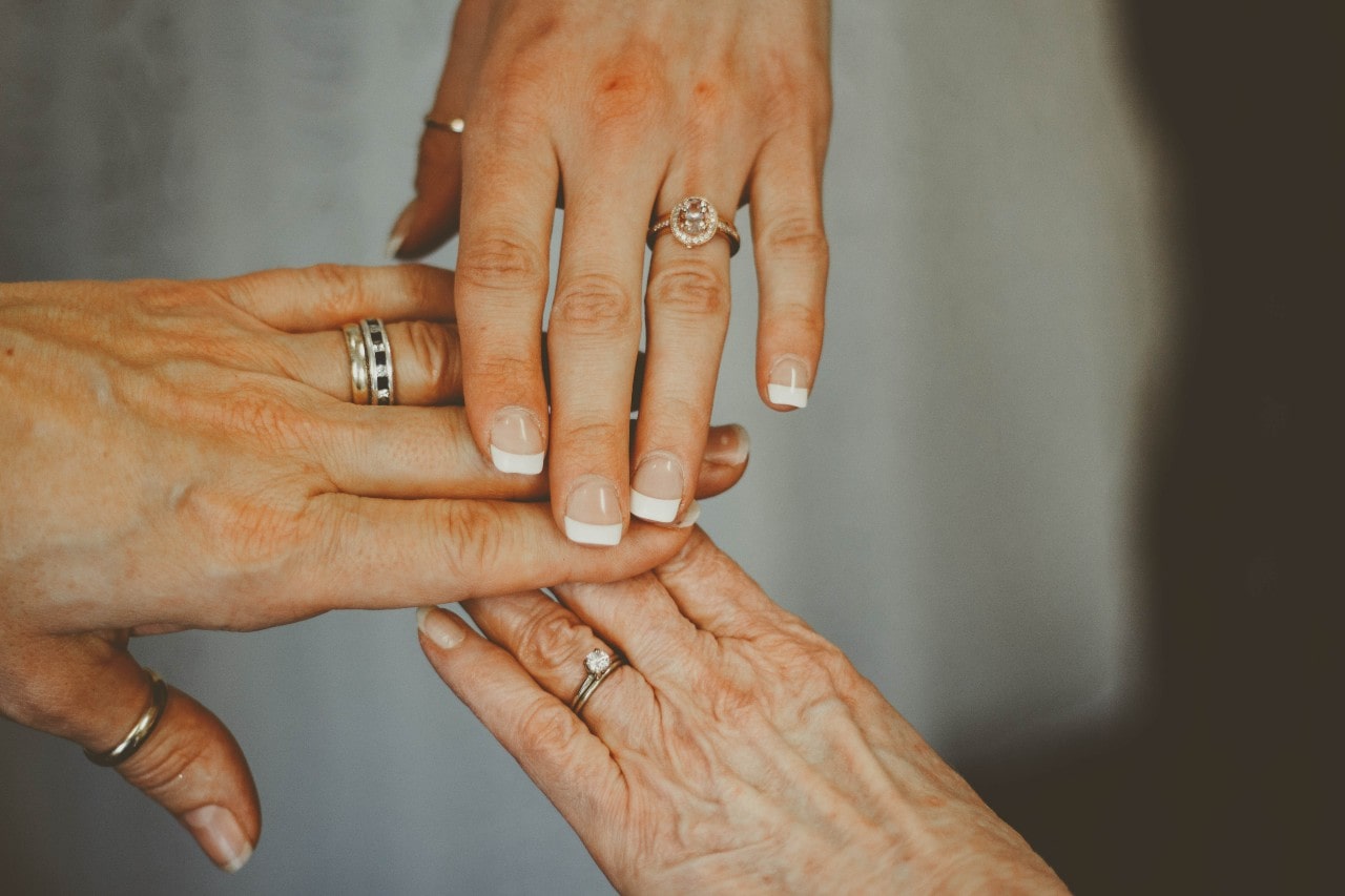 Three generations of hands yellow and rose gold wearing rings, symbolizing love and family connections