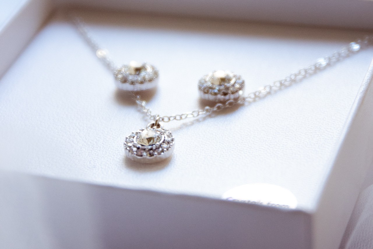 A close-up of a matching diamond earring and necklace set displayed in their box.