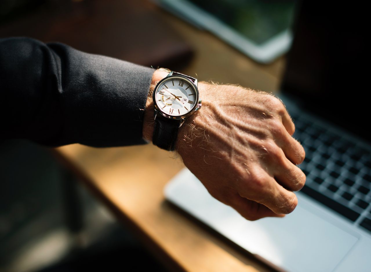 A close-up of a man’s wrist as he checks his watch.